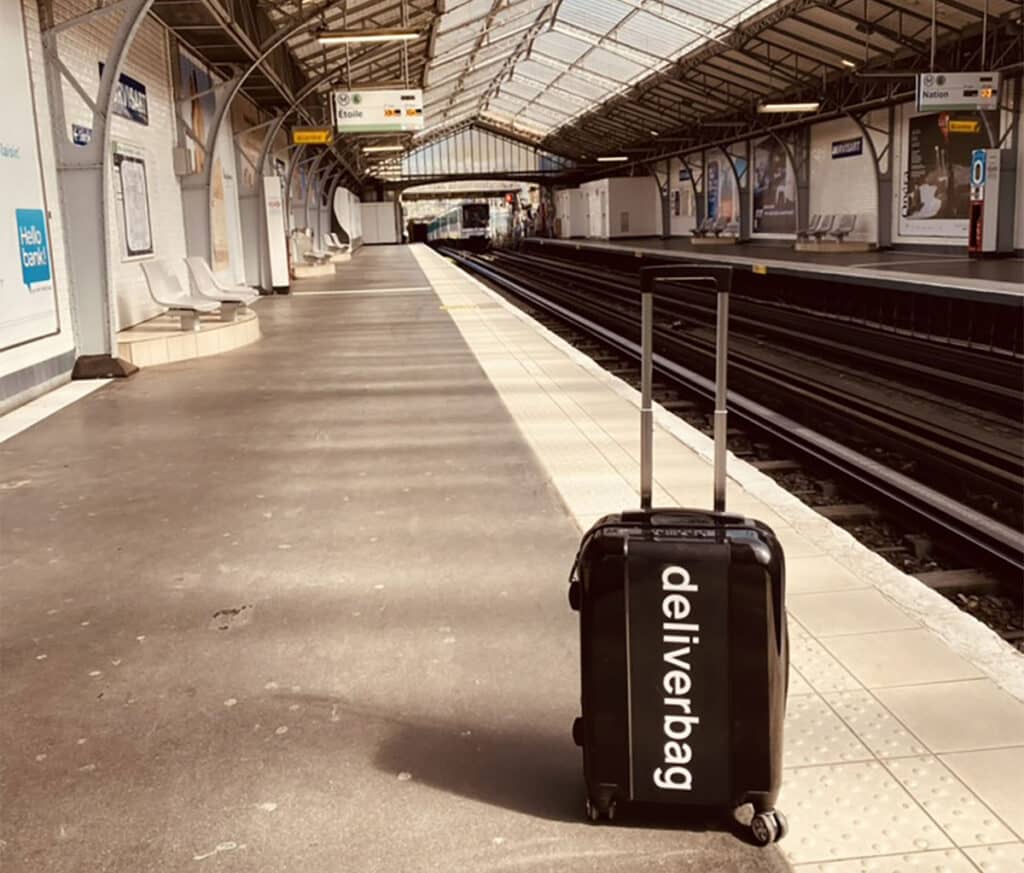 Valise noire Deliverbag posée sur un quai de gare
