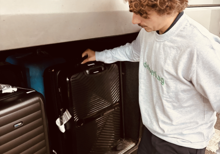 Une personne portant un sweat-shirt gris clair charge une valise noire dans le compartiment à bagages d'un bus, montrant une livraison bagages sécurisée. D'autres valises sont visibles à proximité. Une personne portant un sweat-shirt gris clair charge une valise noire dans le compartiment à bagages d'un bus, montrant une livraison bagages sécurisée. D'autres valises sont visibles à proximité.