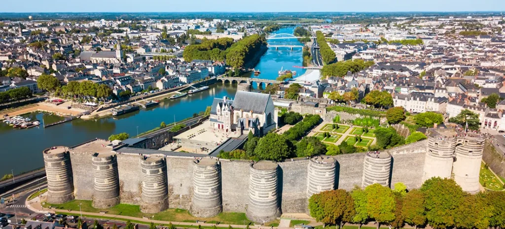 Vue aérienne du château d'Angers, un château médiéval aux murs de pierre massifs et aux tours rondes, entouré de jardins et de la rivière Maine, dans la ville d'Angers, en France.
