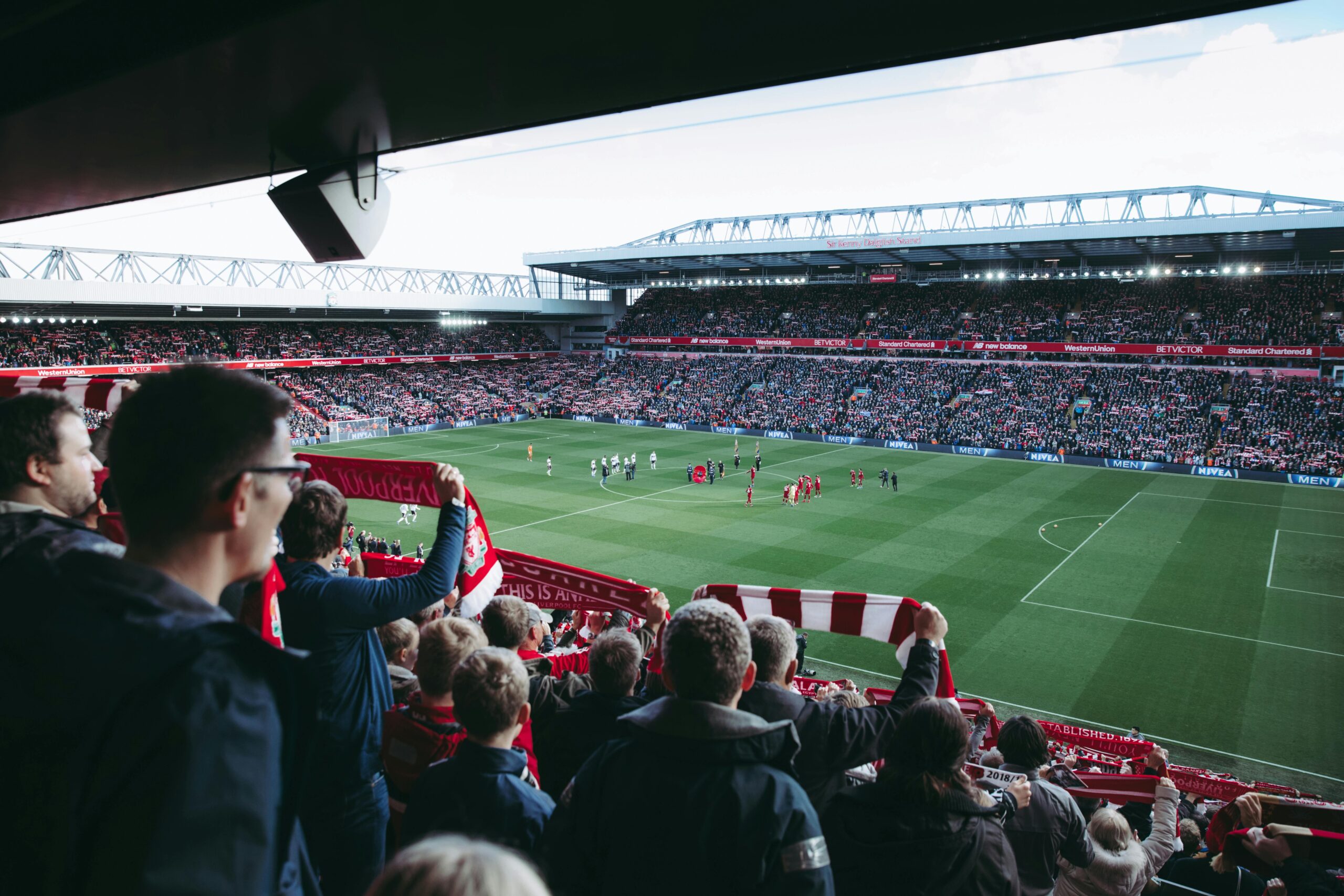 Une foule de supporters de football, dont beaucoup portent des écharpes rouges et blanches, applaudit dans un stade rempli de spectateurs alors que les joueurs se rassemblent sur le terrain avant un match. Une foule de supporters de football, dont beaucoup portent des écharpes rouges et blanches, applaudit dans un stade rempli de spectateurs alors que les joueurs se rassemblent sur le terrain avant un match.