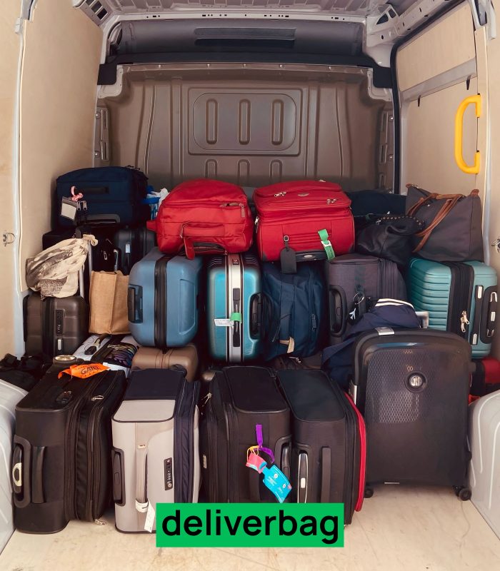 Une variété de valises et de sacs sont empilés à l'arrière d'une camionnette, avec une étiquette verte "deliverbag" au fond - idéal pour la consigne bagages France ou le stockage bagages sécurisé lors d'un voyage ou d'un service de messagerie.
