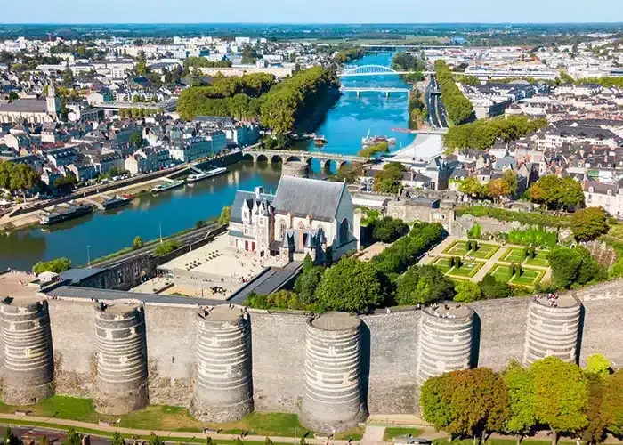 Aerial view of the Château d'Angers, a medieval castle with massive stone walls and round towers, surrounded by gardens and the River Maine, in the town of Angers, France.