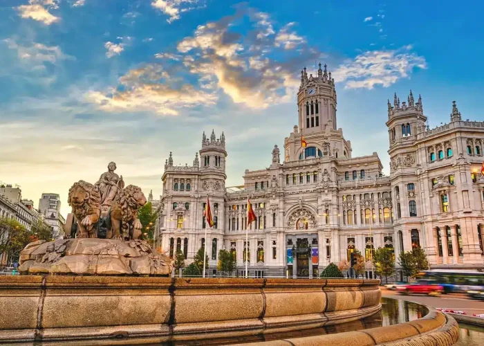Vue de la fontaine de Cibeles avec le grand Palacio de Cibeles en arrière-plan sous un ciel nocturne vibrant à Madrid, en Espagne. Le bâtiment historique et la statue sont illuminés par la lumière dorée du soleil.