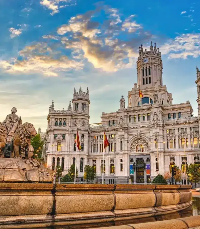 Vue de la fontaine de Cibeles avec le grand Palacio de Cibeles en arrière-plan sous un ciel nocturne vibrant à Madrid, en Espagne. Le bâtiment historique et la statue sont illuminés par la lumière dorée du soleil.