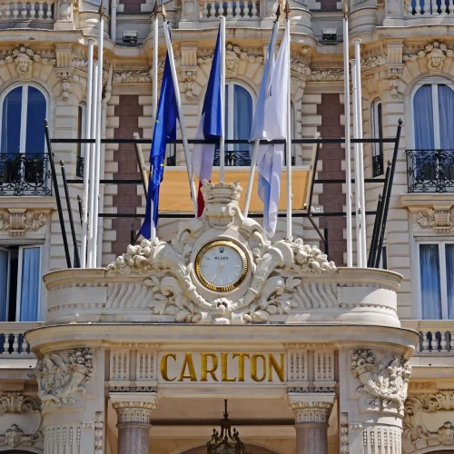 L'entrée somptueuse de l'hôtel Carlton est ornée d'une horloge dorée, de sculptures décoratives, de plusieurs drapeaux et d'élégants détails architecturaux.